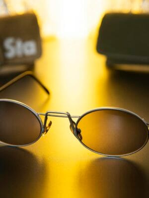 Close-up of sleek sunglasses on a shiny black surface with warm golden light.