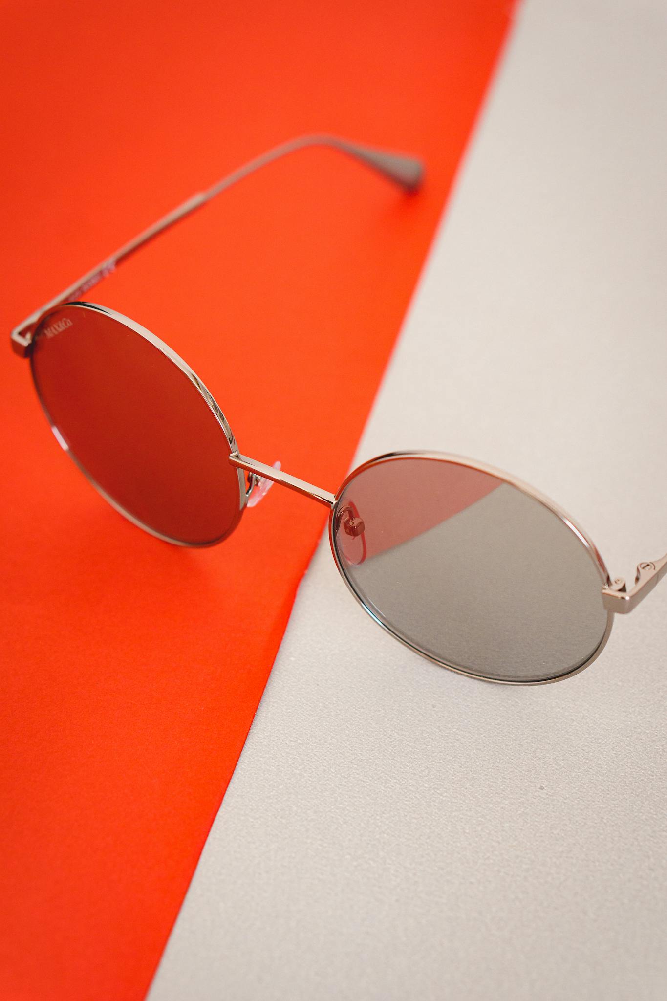 Minimalist close-up of round sunglasses on vibrant two-tone background. Perfect for fashion displays.