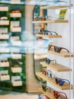 Stylish sunglasses neatly arranged on wooden shelves in a modern retail store setting.