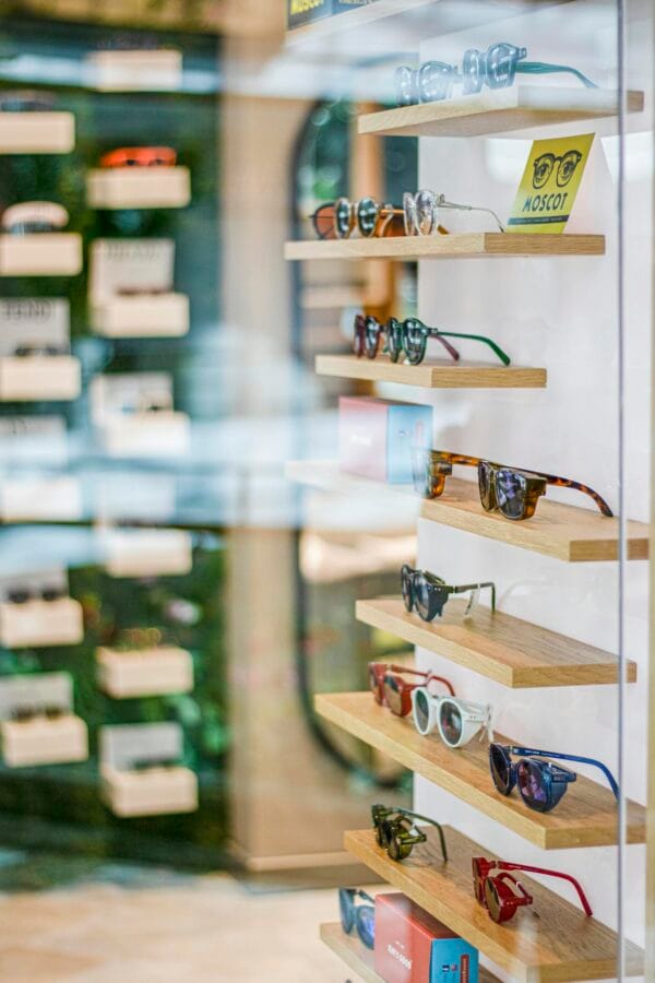 Stylish sunglasses neatly arranged on wooden shelves in a modern retail store setting.